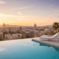 Appart hotel Barcelone : vue panoramique depuis une piscine sur le toit avec des chaises longues, face aux toits de la ville au coucher du soleil. Appart hotel Barcelone : vue panoramique depuis une piscine sur le toit avec des chaises longues, face aux toits de la ville au coucher du soleil.